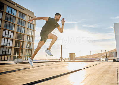 Buy stock photo Shot of a sporty young man out on a rooftop for a workout