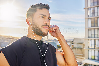 Buy stock photo Shot of a man wearing earphones while standing outside in exercise clothes