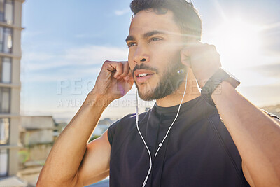 Buy stock photo Shot of a man wearing earphones while standing outside in exercise clothes