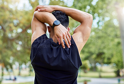 Buy stock photo Rearview shot of a sporty young man stretching his arms while exercising outdoors