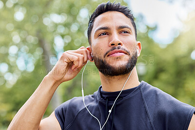 Buy stock photo Shot of a sporty young man listening to music while exercising outdoors