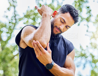 Buy stock photo Low angle shot of a sporty young man experiencing elbow pain while exercising outdoors