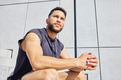 Buy stock photo Low angle shot of a sporty young man taking a break while exercising outdoors