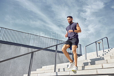 Buy stock photo Low angle shot of a sporty young man running down a staircase while exercising outdoors
