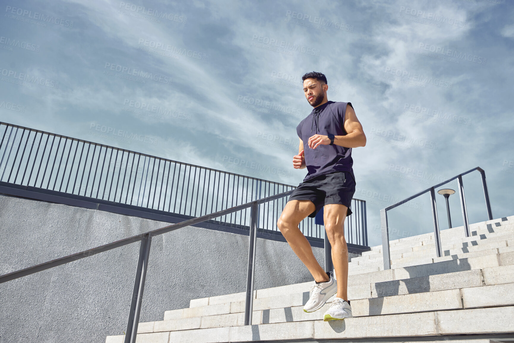 Buy stock photo Low angle shot of a sporty young man running down a staircase while exercising outdoors