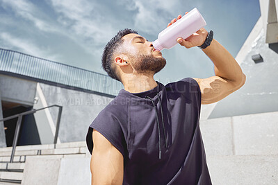 Buy stock photo Shot of a sporty young man drinking water while exercising outdoors