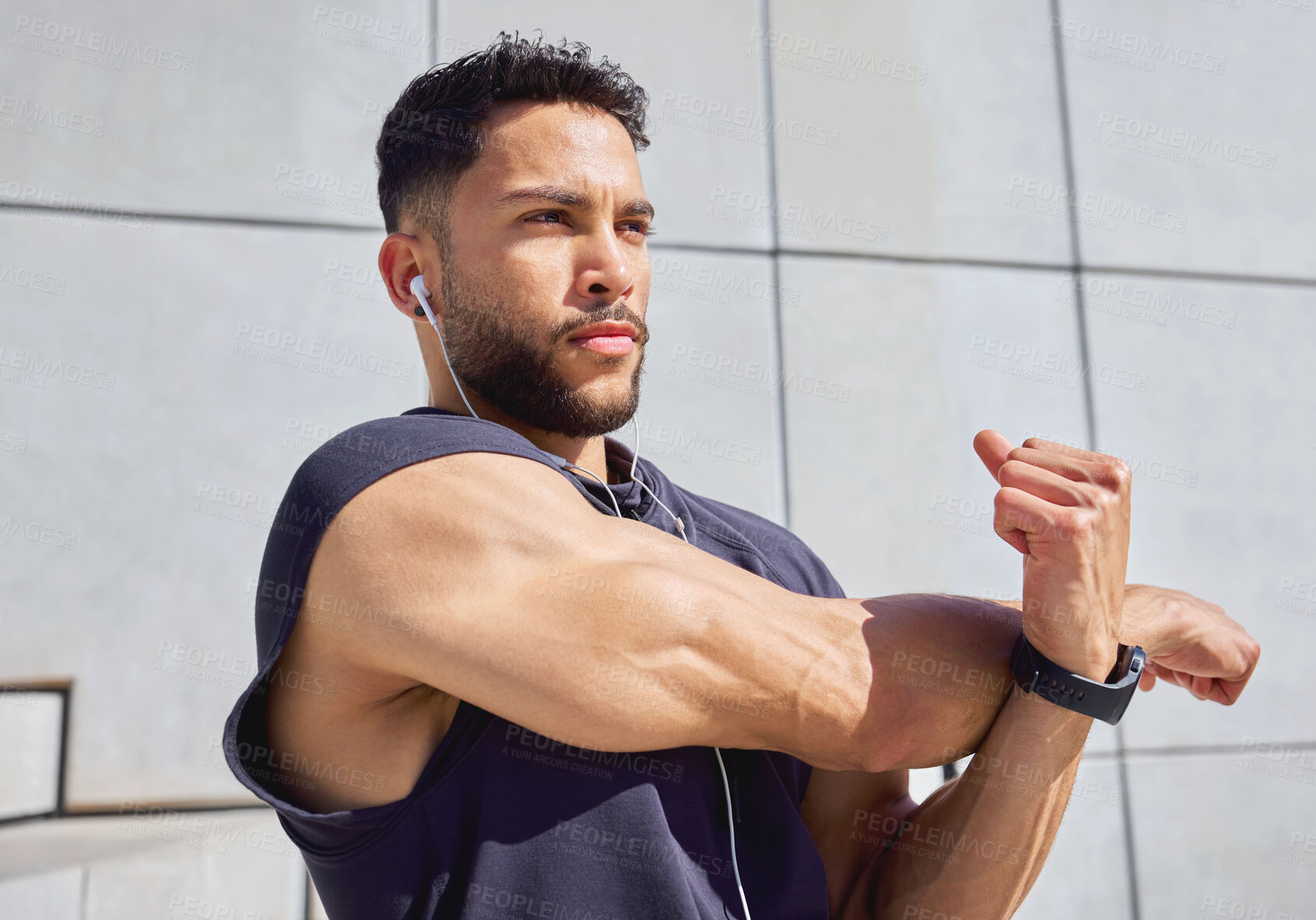 Buy stock photo Shot of a sporty young man listening to music and stretching his arms while exercising outdoors