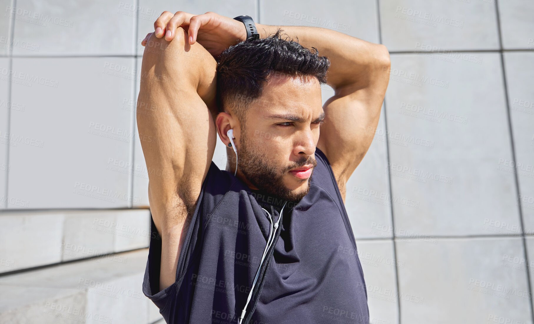 Buy stock photo Shot of a sporty young man listening to music and stretching his arms while exercising outdoors