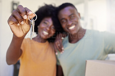 Buy stock photo Shot of a young couple holding the keys to their new house
