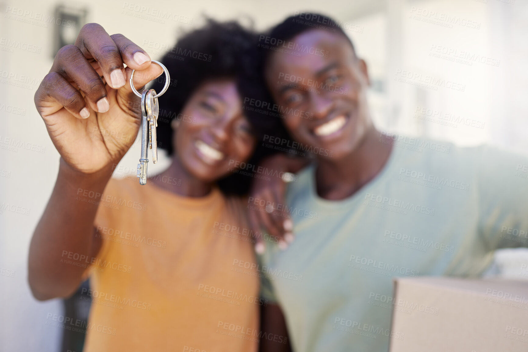 Buy stock photo Shot of a young couple holding the keys to their new house