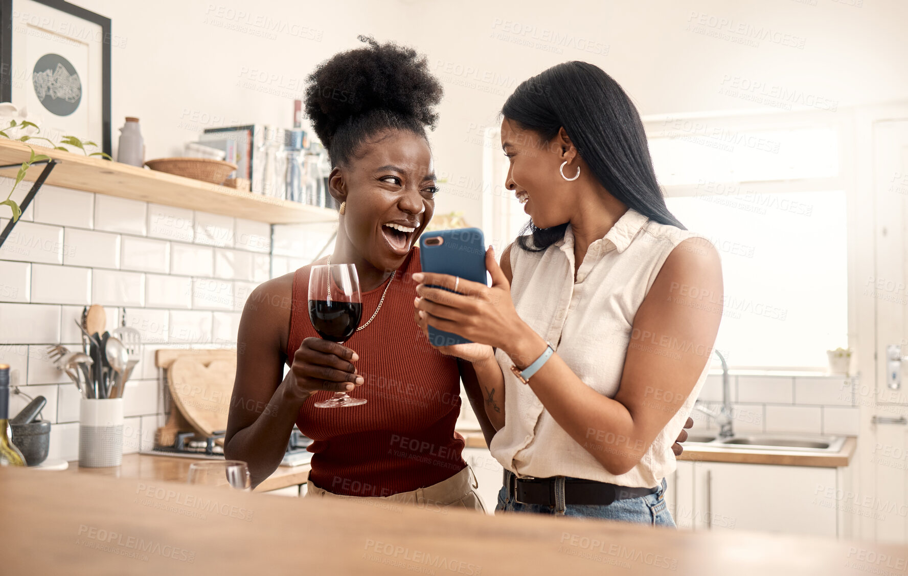 Buy stock photo Shot of two young friends using a phone while spending time together at home