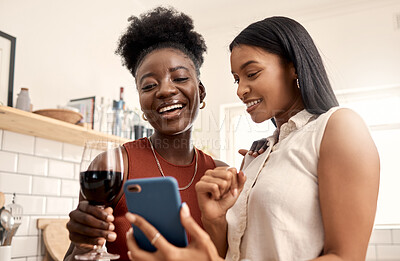 Buy stock photo Shot of two young friends using a phone while spending time together at home