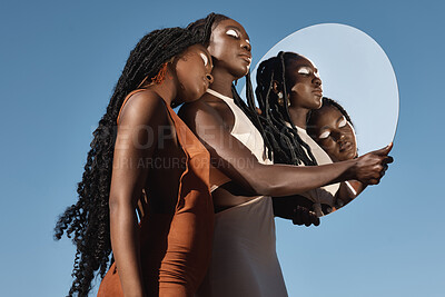 Buy stock photo Shot of two attractive young women holding a mirror with their reflection in it against a sky background