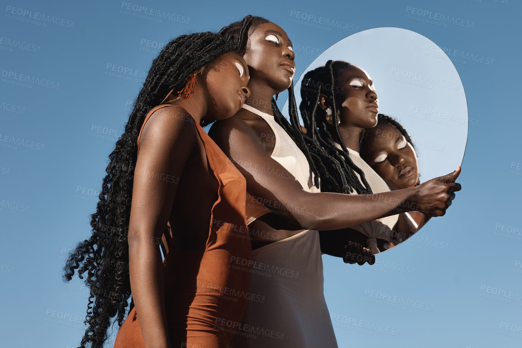 Buy stock photo Shot of two attractive young women holding a mirror with their reflection in it against a sky background