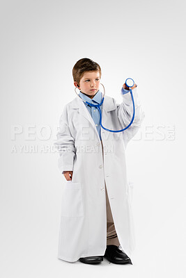 Buy stock photo Little boy, doctor and stethoscope with uniform in studio for heart rate, checkup or healthcare on a white background. Child, kid or junior cardiologist play with health tool or equipment for pretend