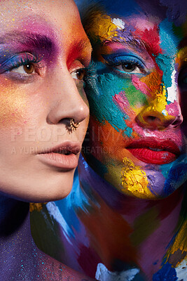 Buy stock photo Studio shot of two young women posing with multi-coloured paint on her face