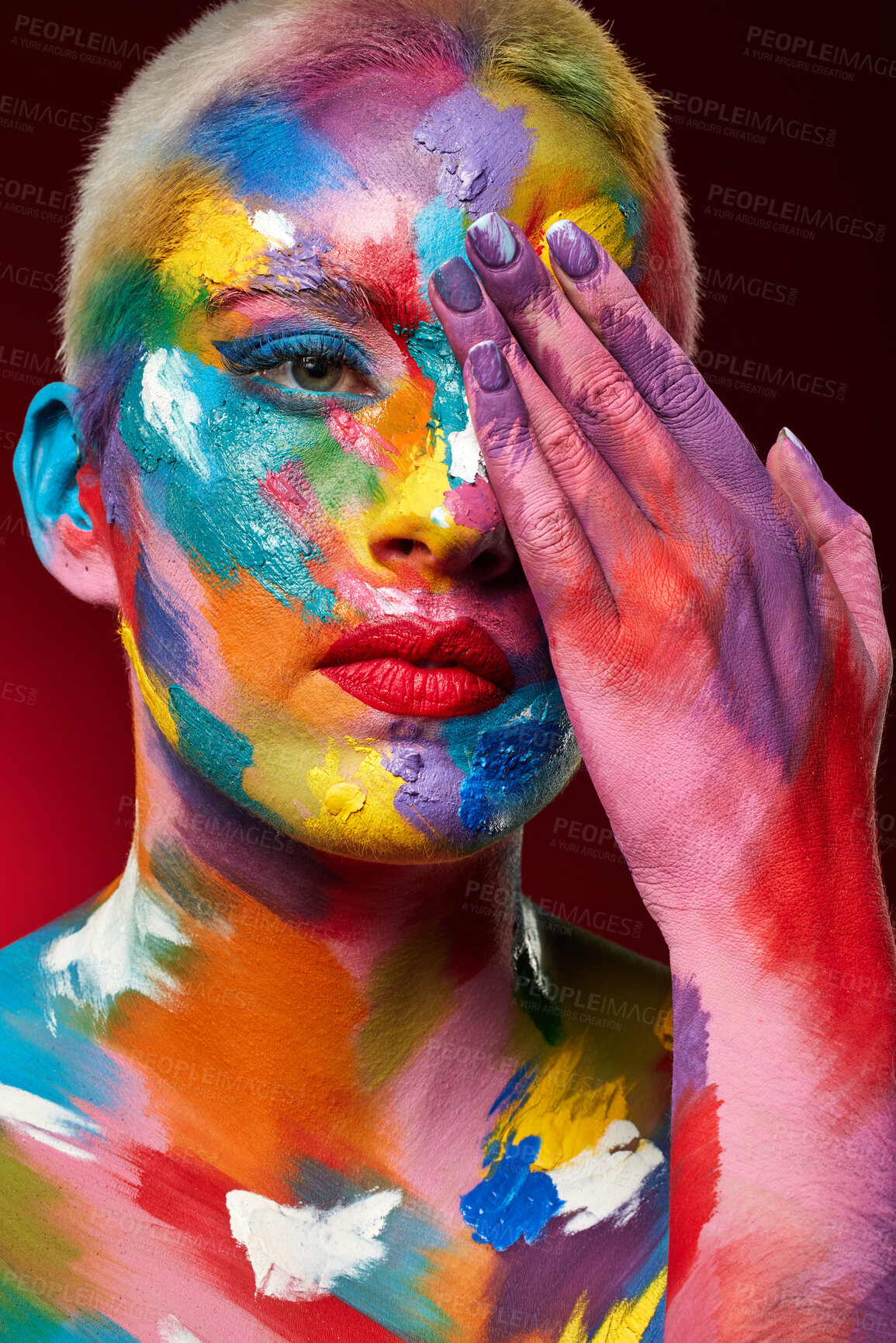 Buy stock photo Studio shot of a young woman posing with multi-coloured paint on her face