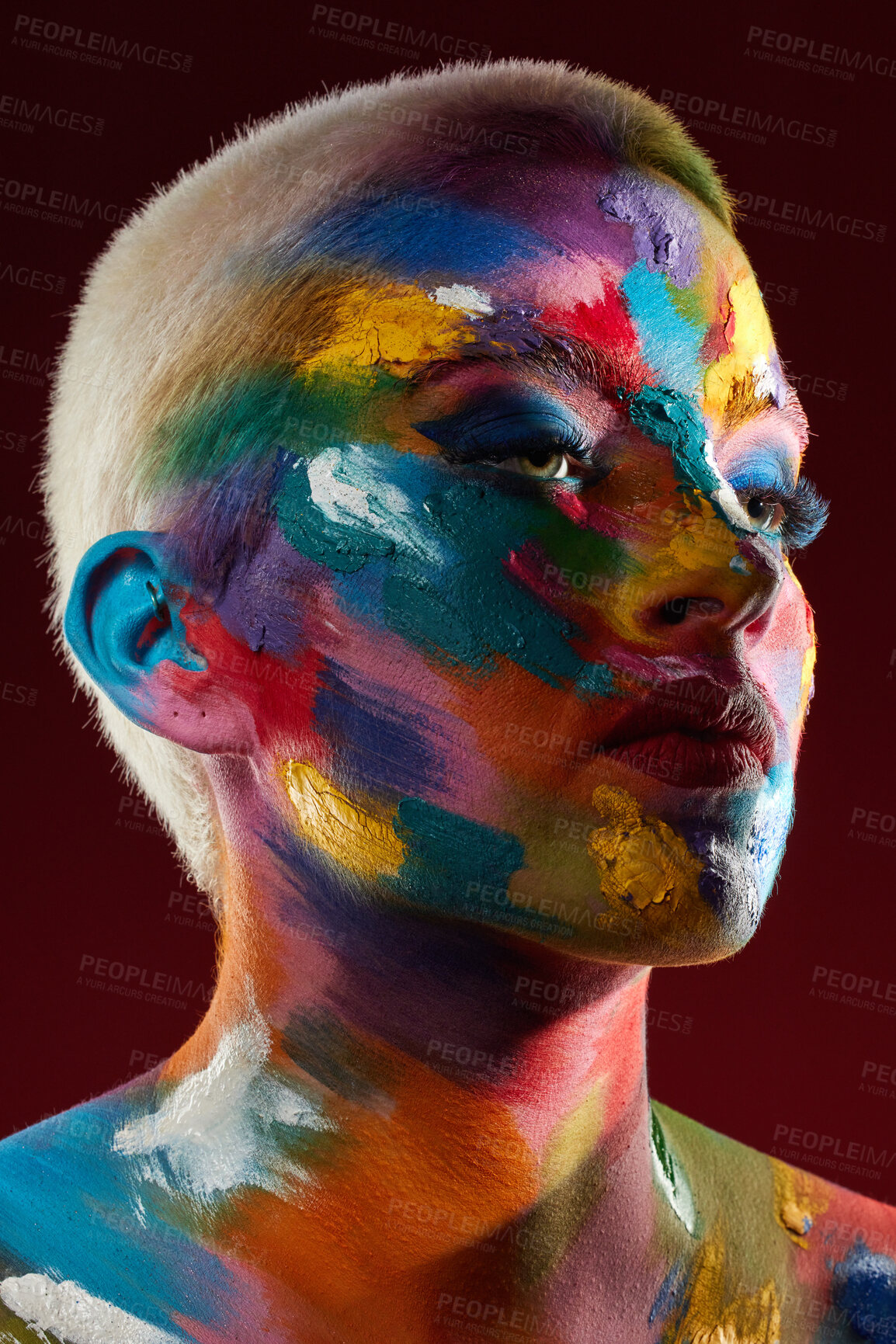 Buy stock photo Studio shot of a young woman posing with multi-coloured paint on her face