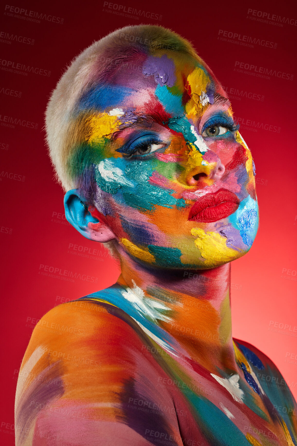 Buy stock photo Studio shot of a young woman posing with multi-coloured paint on her face