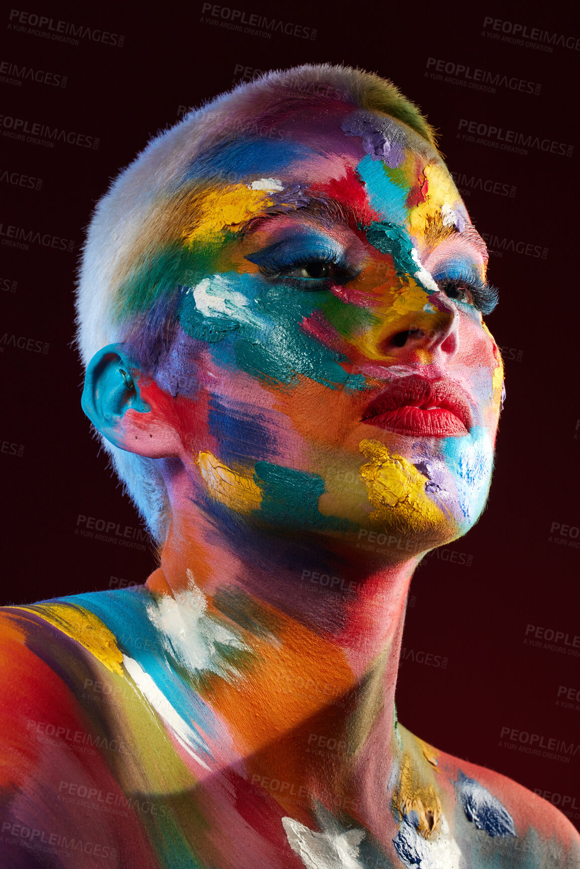 Buy stock photo Studio shot of a young woman posing with multi-coloured paint on her face