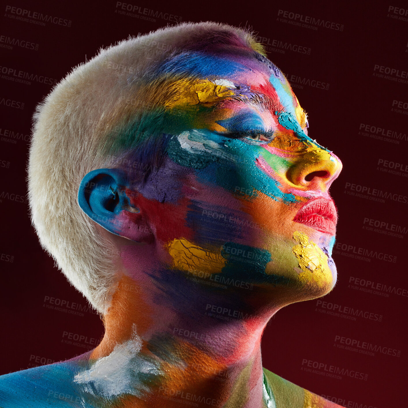 Buy stock photo Studio shot of a young woman posing with multi-coloured paint on her face