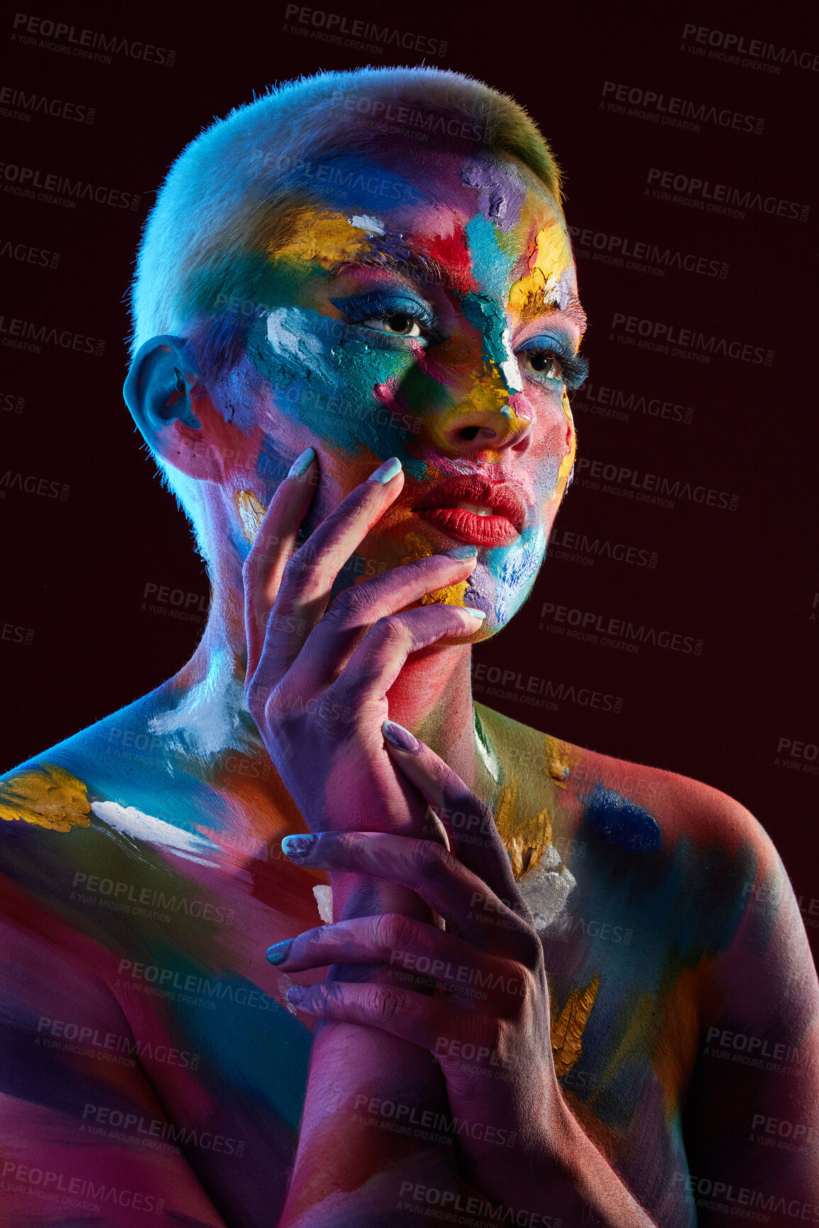 Buy stock photo Studio shot of a young woman posing with multi-coloured paint on her face