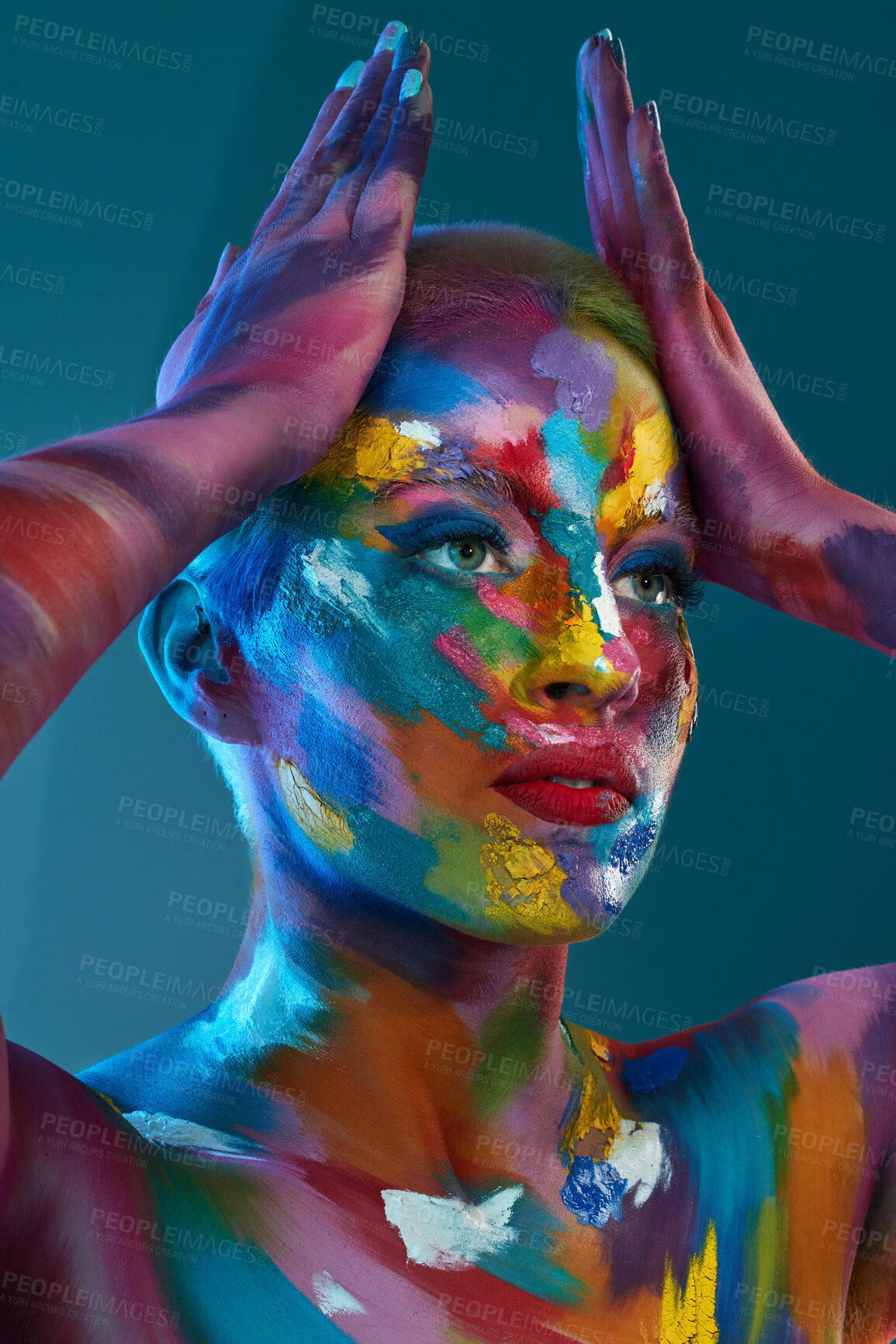 Buy stock photo Studio shot of a young woman posing with multi-coloured paint on her face