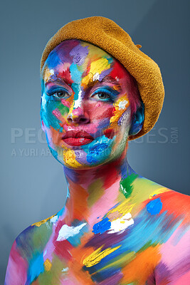 Buy stock photo Studio shot of a young woman posing with multi-coloured paint on her face and a french hat on her head