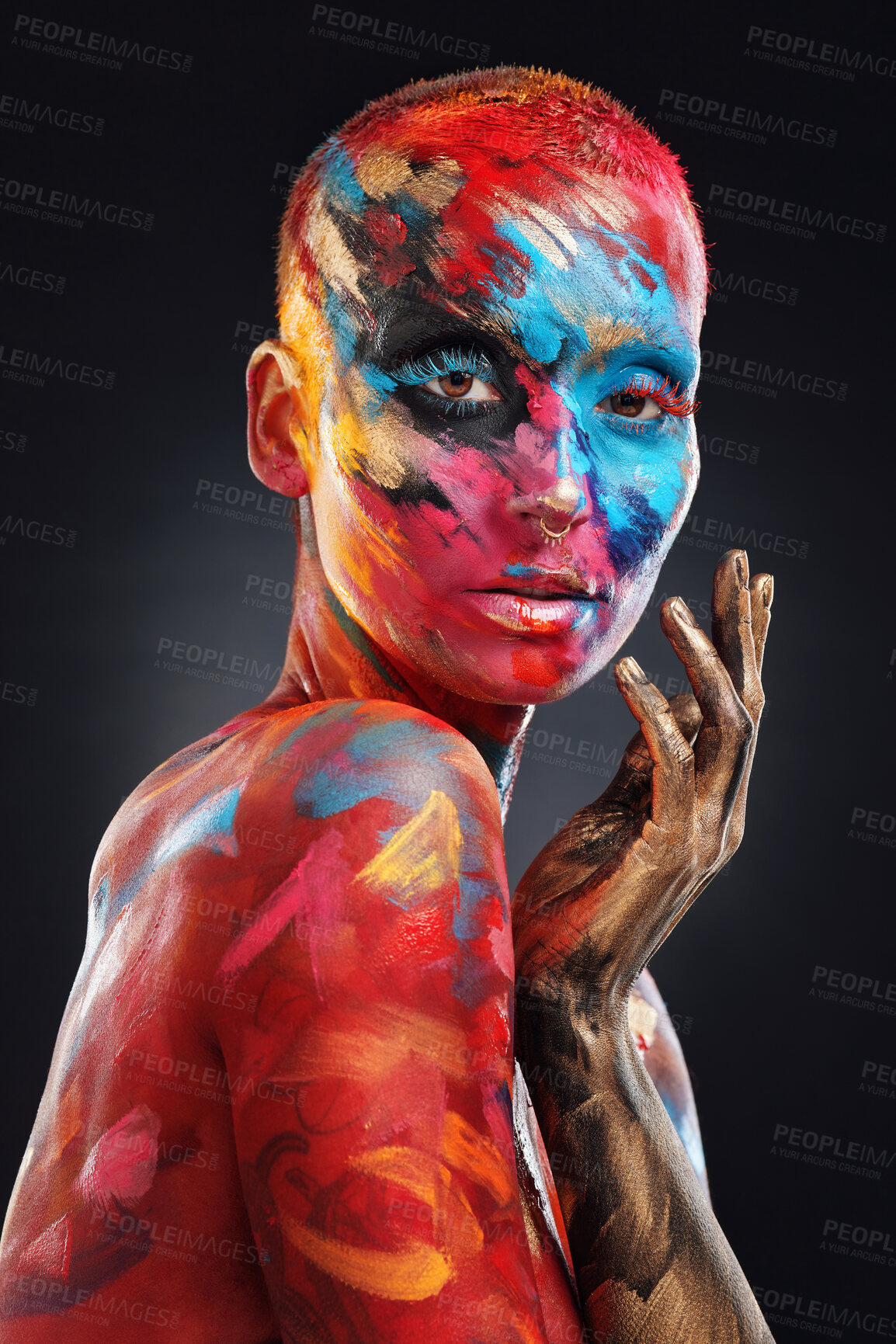 Buy stock photo Shot of an attractive young woman posing alone in the studio with paint on her face and body