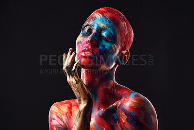 Buy stock photo Shot of an attractive young woman posing alone in the studio with paint on her face and body