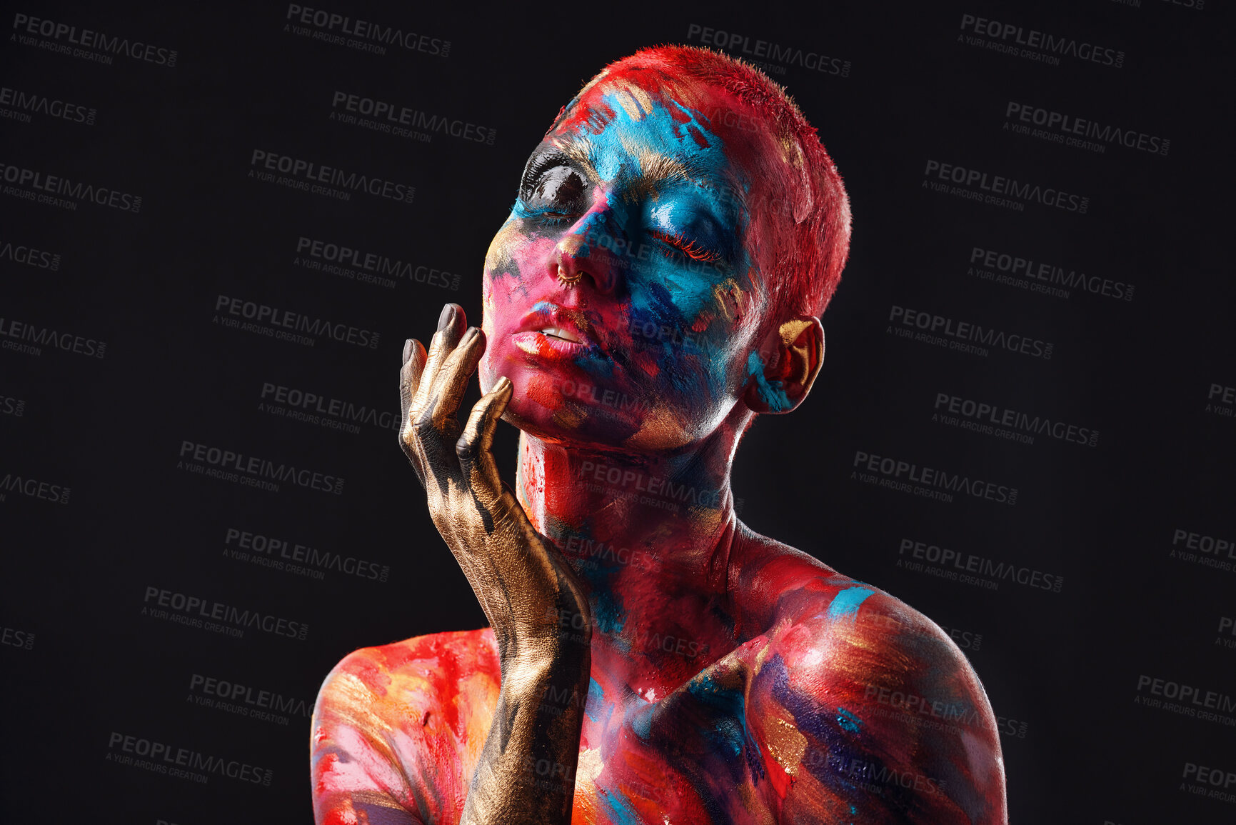 Buy stock photo Shot of an attractive young woman posing alone in the studio with paint on her face and body