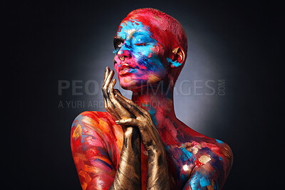 Buy stock photo Shot of an attractive young woman posing alone in the studio with paint on her face and body