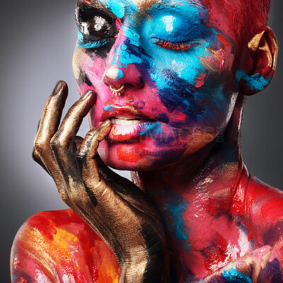 Buy stock photo Shot of an attractive young woman posing alone in the studio with paint on her face