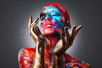 Buy stock photo Shot of an attractive young woman posing alone in the studio with paint on her face and body