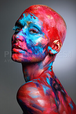 Buy stock photo Shot of an attractive young woman posing alone in the studio with paint on her face and body