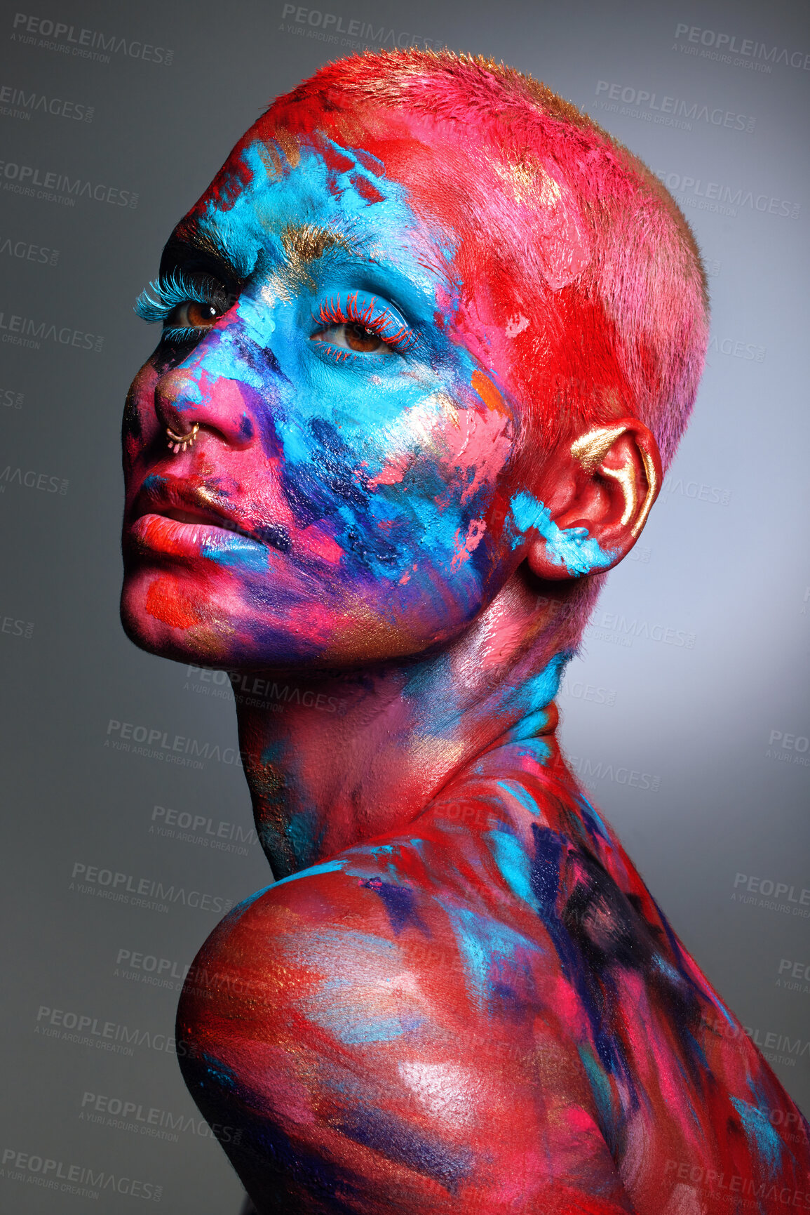 Buy stock photo Shot of an attractive young woman posing alone in the studio with paint on her face and body