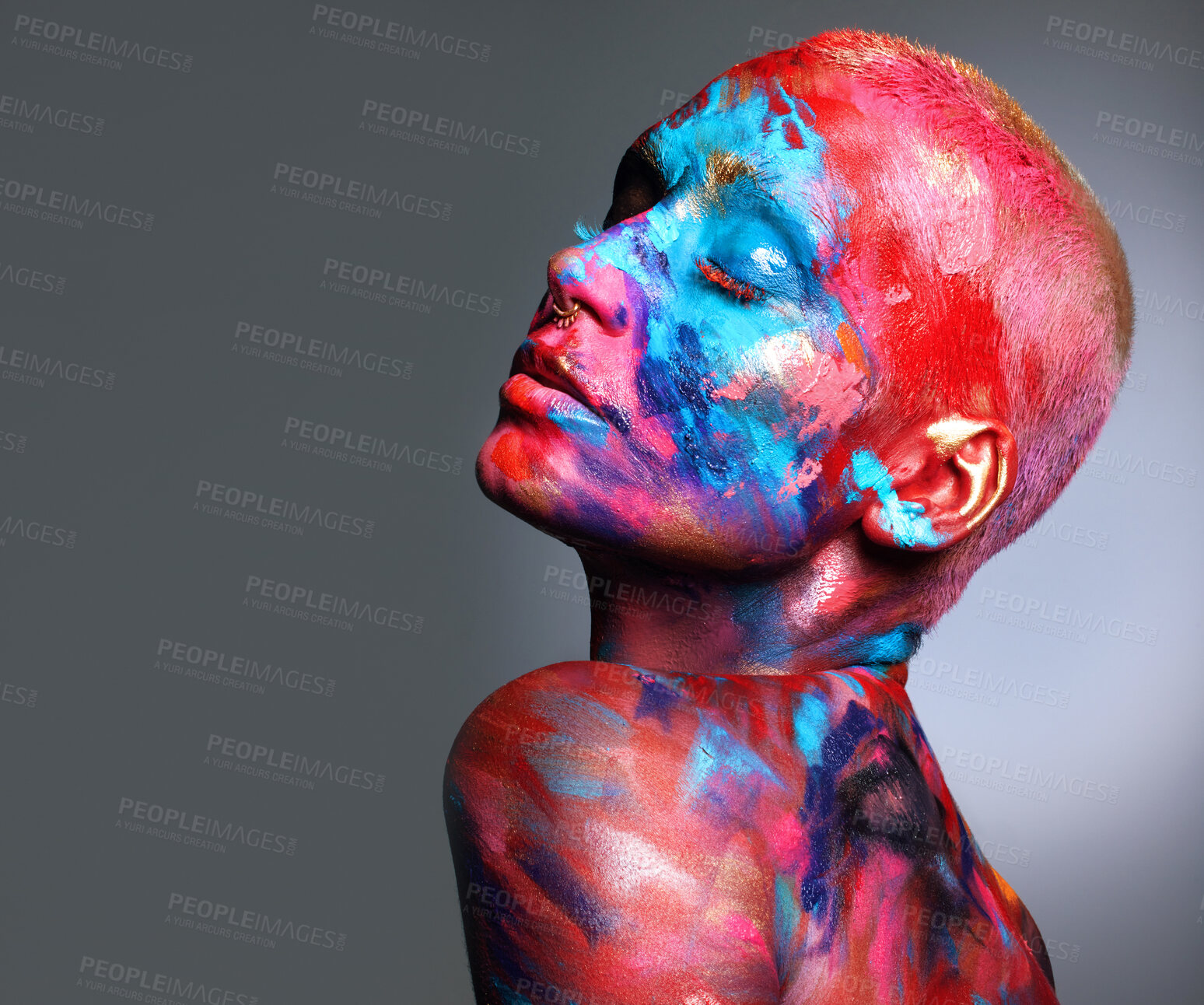 Buy stock photo Shot of an attractive young woman posing alone in the studio with paint on her face and body