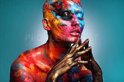 Buy stock photo Shot of an attractive young woman posing alone in the studio with paint on her face and body