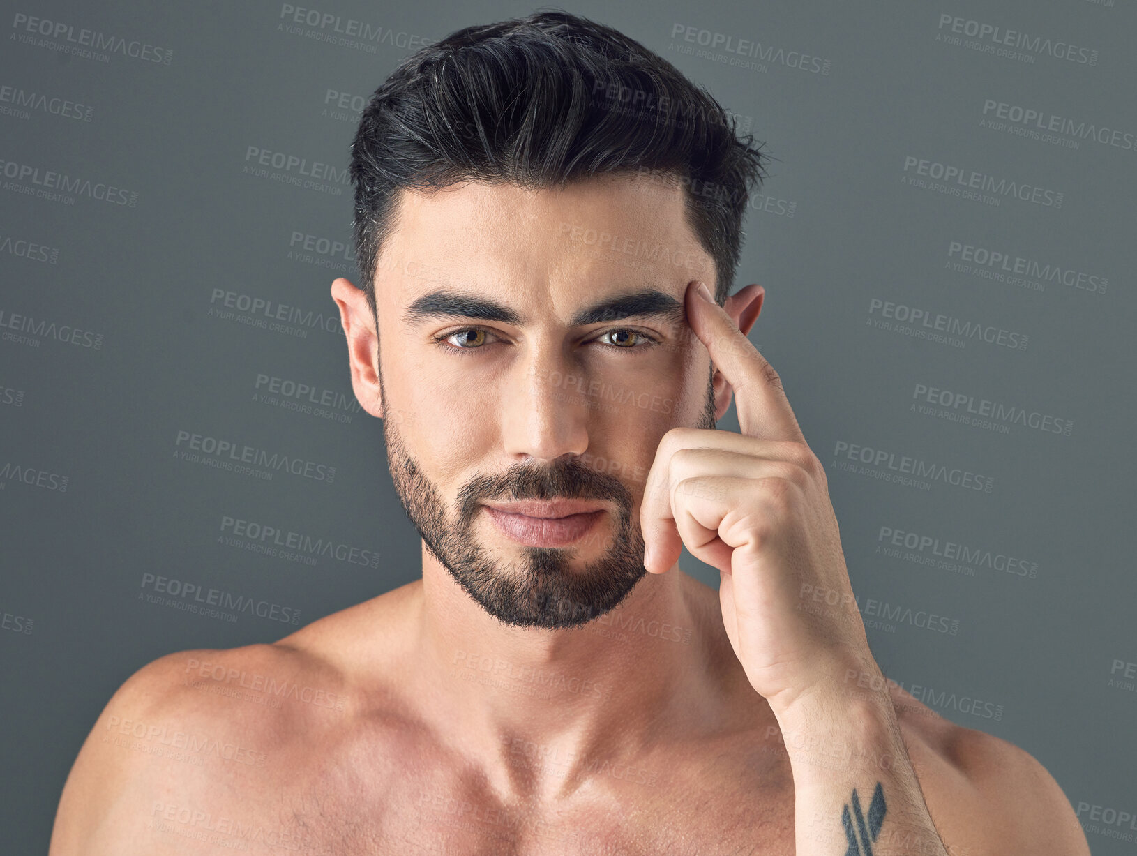 Buy stock photo Shot of a handsome young man posing against a grey background