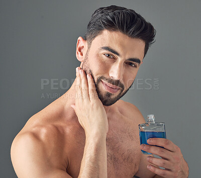 Buy stock photo Shot of a handsome young man applying aftershave