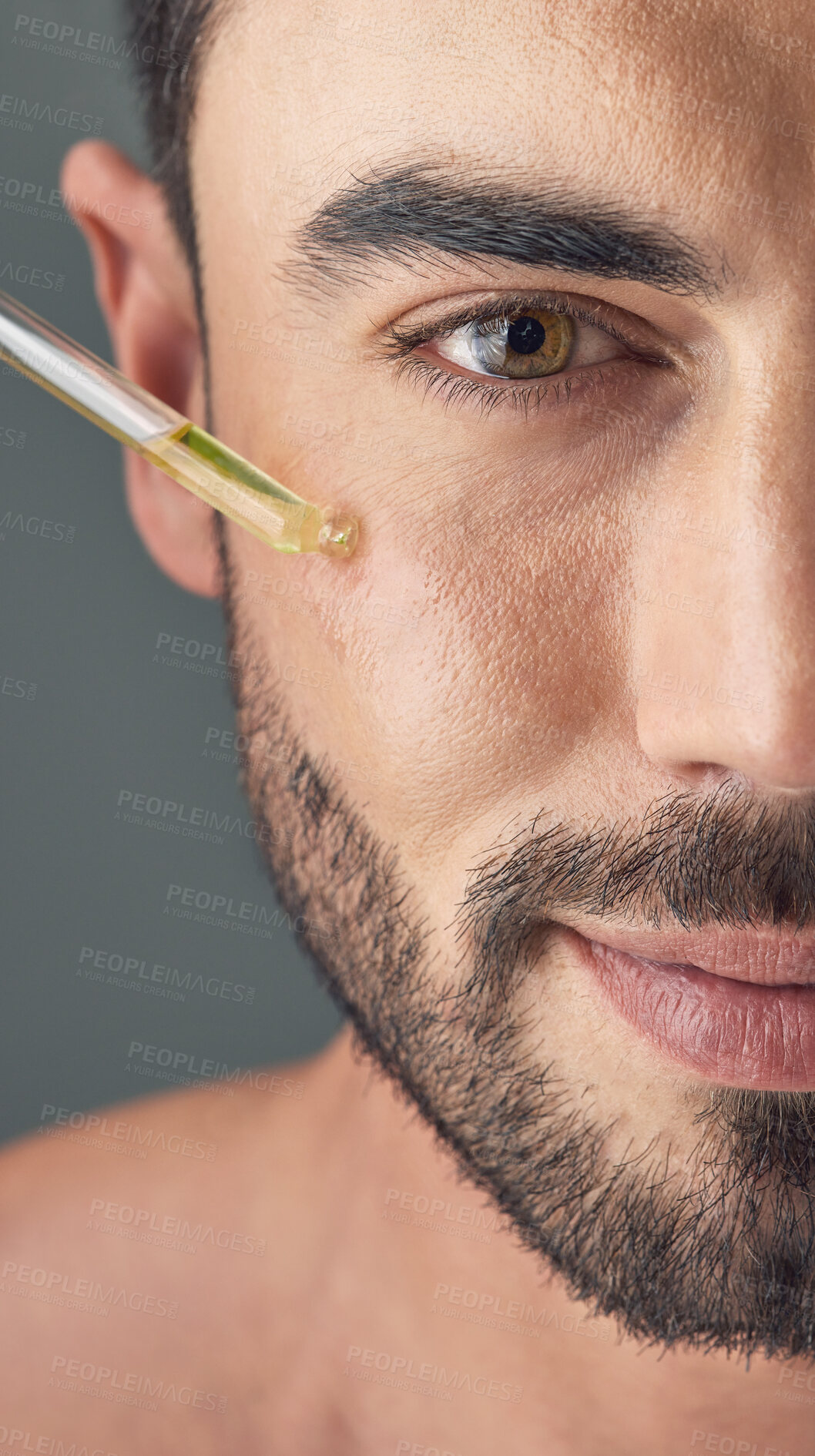 Buy stock photo Shot of a handsome young man applying serum to his face with a dropper