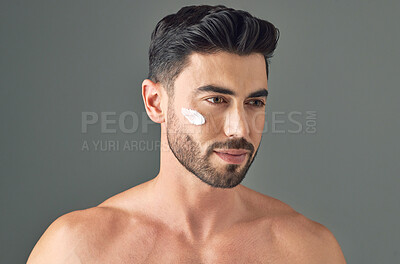 Buy stock photo Studio shot of a handsome young man posing with moisturiser on his face