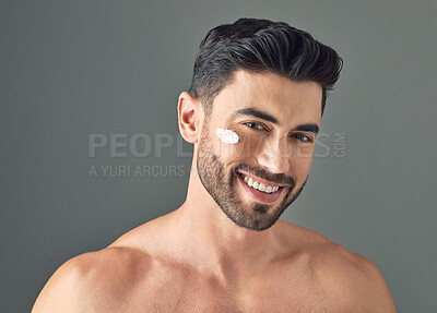 Buy stock photo Studio shot of a handsome young man posing with moisturiser on his face