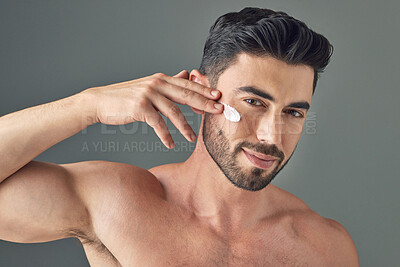 Buy stock photo Studio shot of a handsome young man posing with moisturiser on his face