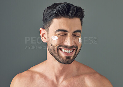 Buy stock photo Studio shot of a handsome young man posing with moisturiser on his face