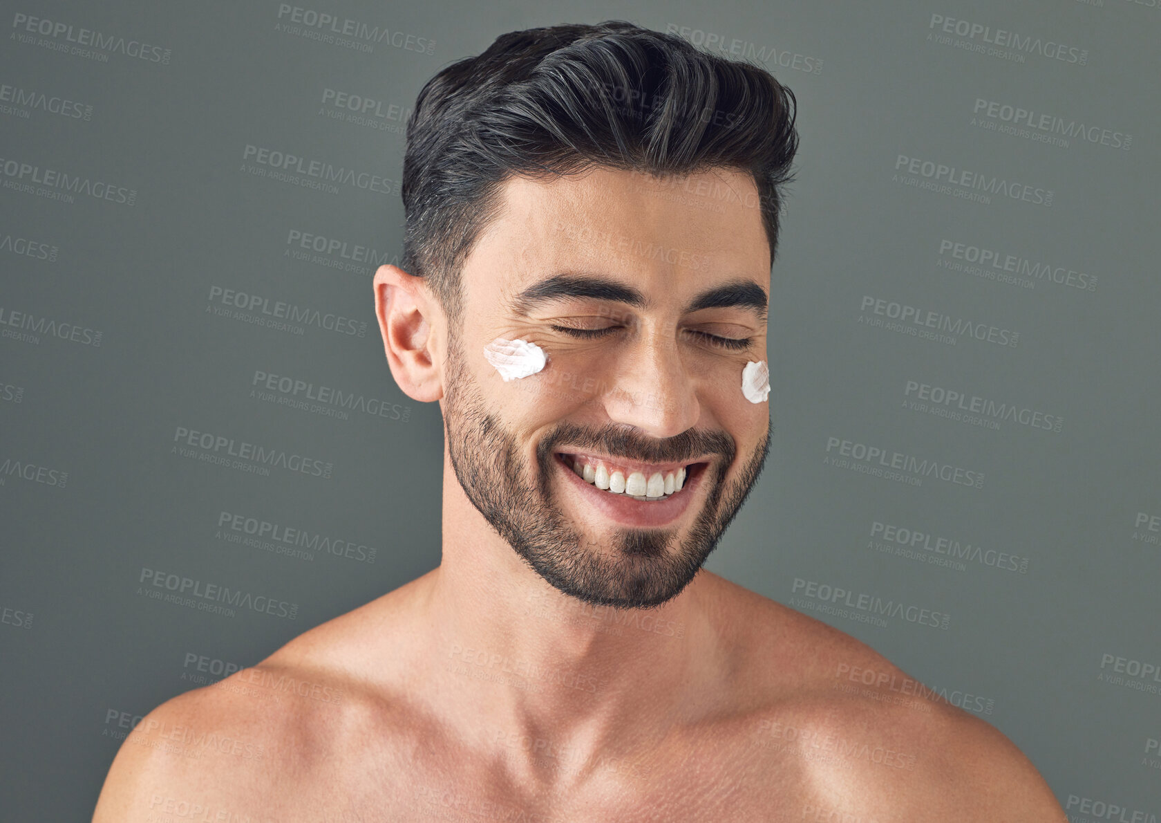 Buy stock photo Studio shot of a handsome young man posing with moisturiser on his face