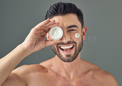 Buy stock photo Studio shot of a handsome young man holding up a skincare product