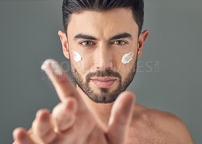 Buy stock photo Studio shot of a handsome young man posing with moisturiser on his face