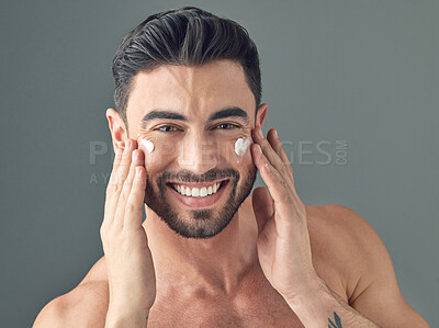 Buy stock photo Studio shot of a handsome young man posing with moisturiser on his face