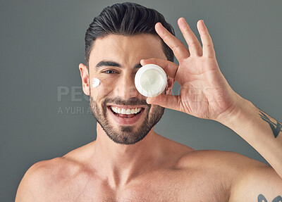 Buy stock photo Studio shot of a handsome young man holding up a skincare product